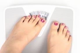 A woman standing on a weight machine, looking down, symbolizing the struggles and frustrations