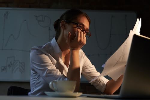 Tired accountant looking through papers in office at night Chronic Pain
